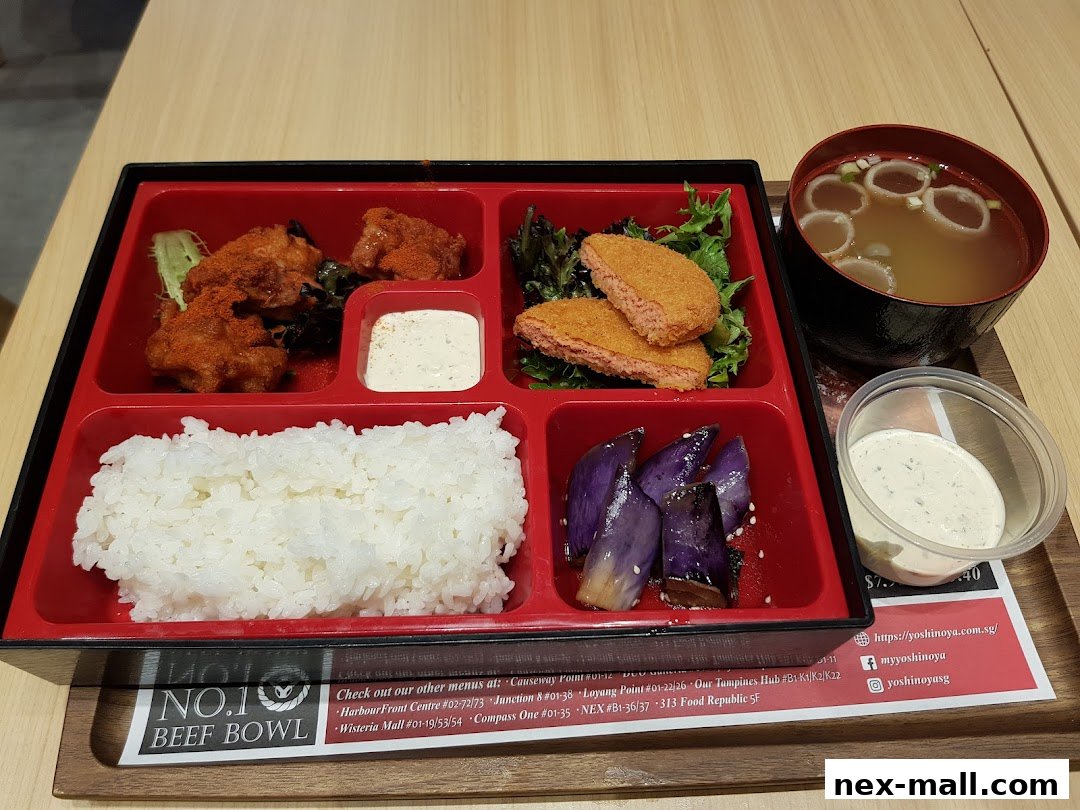 A bento box meal from Yoshinoya with fried chicken, rice, eggplant, and soup.