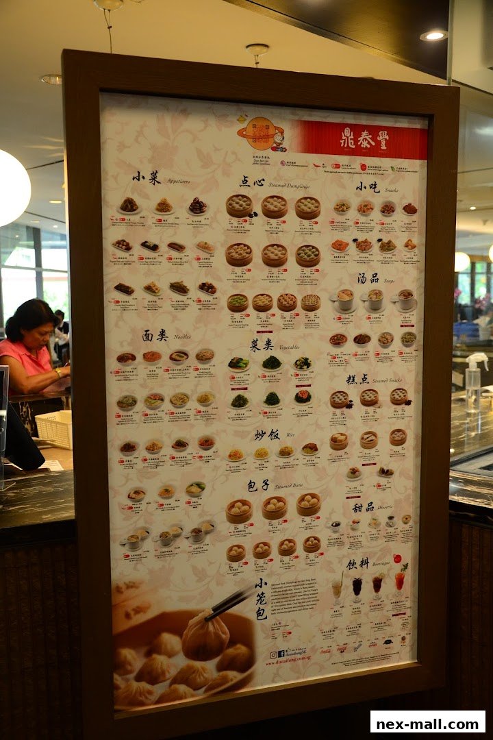 A menu board for Din Tai Fung restaurant, showcasing various dumplings, noodles, vegetables, rice, and drinks.