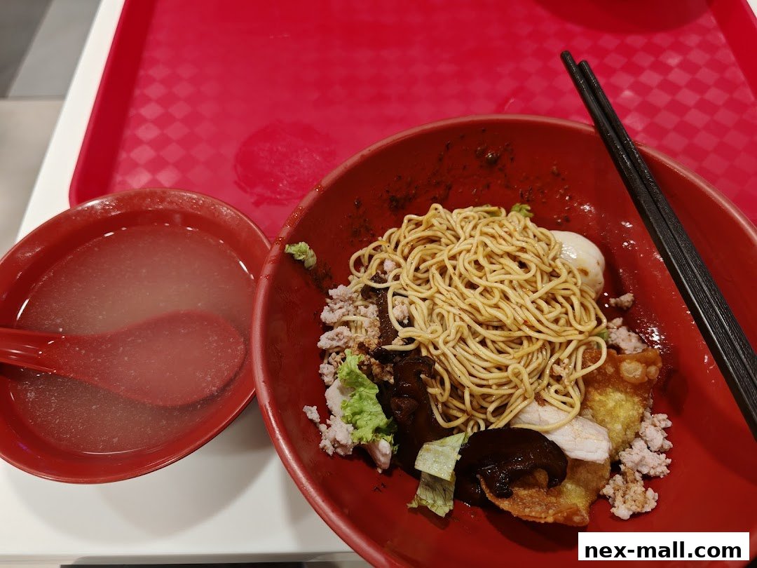 A bowl of noodles with minced meat, mushrooms, and a side of soup.