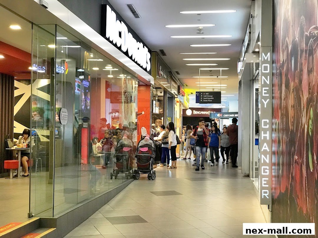 A busy shopping mall corridor with a McDonald's and a money changer shop.