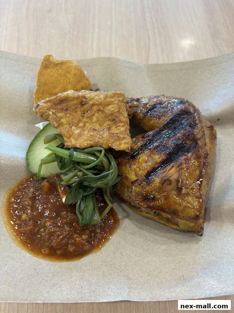 A close-up of Ayam Penyet with grilled chicken, tempeh, vegetables, and sambal.