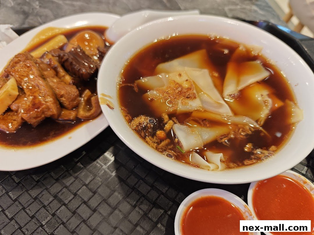 A close-up shot of two plates of delicious food, likely a savory noodle dish and braised items.
