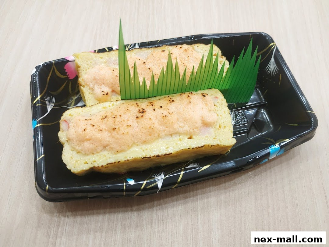 Two pieces of tamagoyaki sushi topped with creamy sauce and garnished with green plastic leaves.