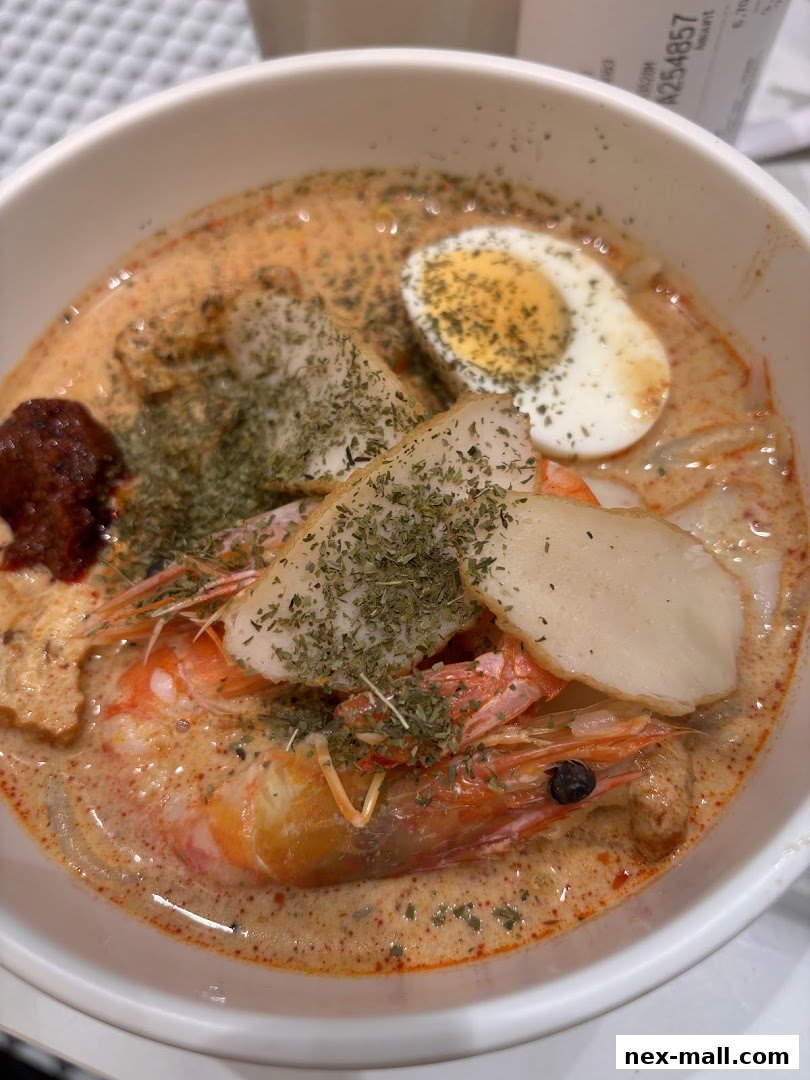 A close-up shot of a delicious bowl of Laksa with prawns, egg, and fish cake.