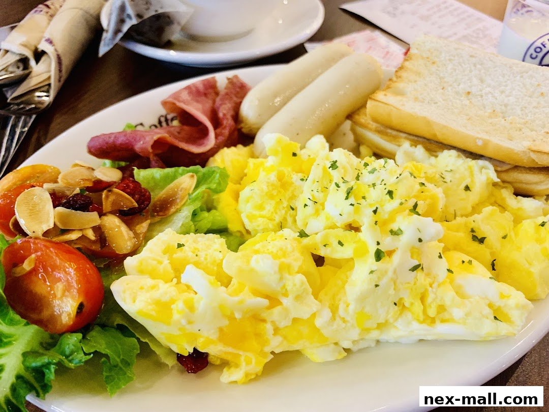 A delicious breakfast plate with scrambled eggs, sausages, toast, and a side salad.