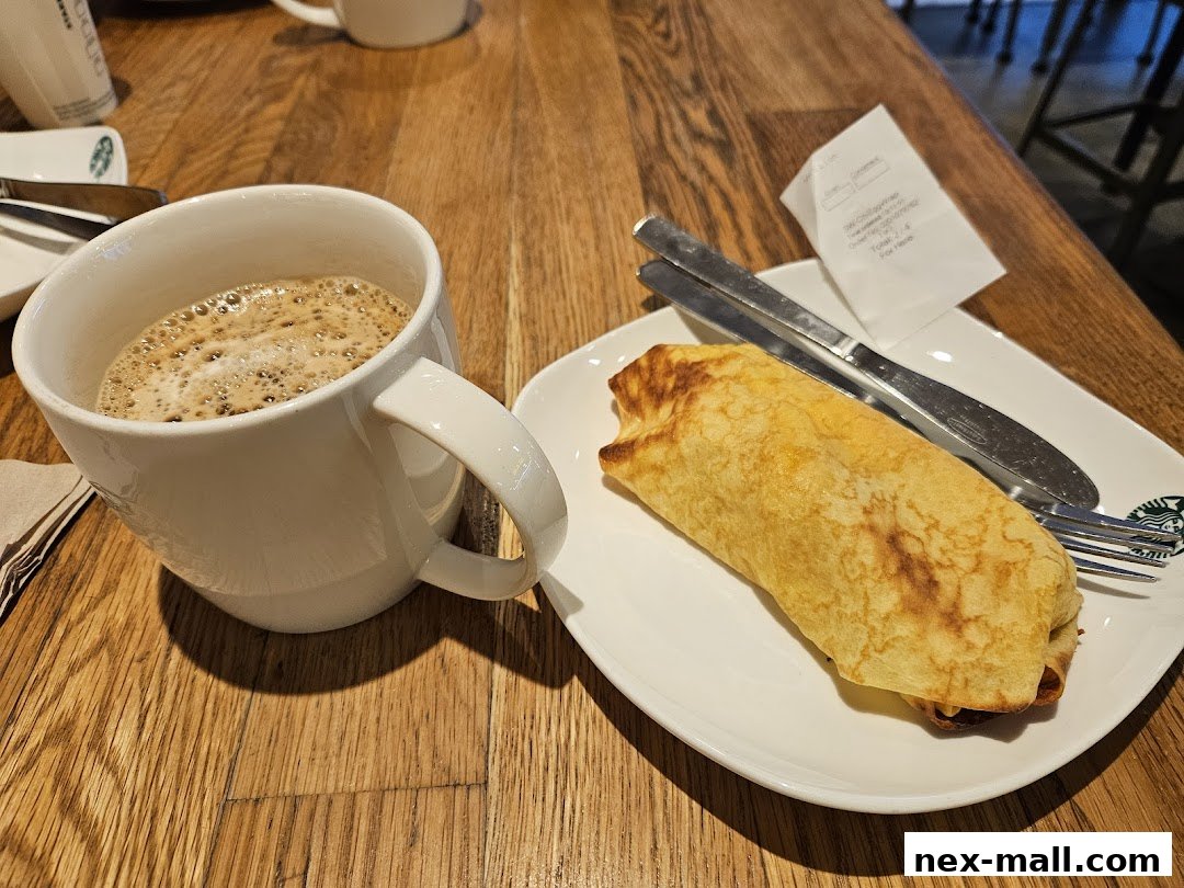 A cup of coffee and a pastry on a wooden table at Starbucks.