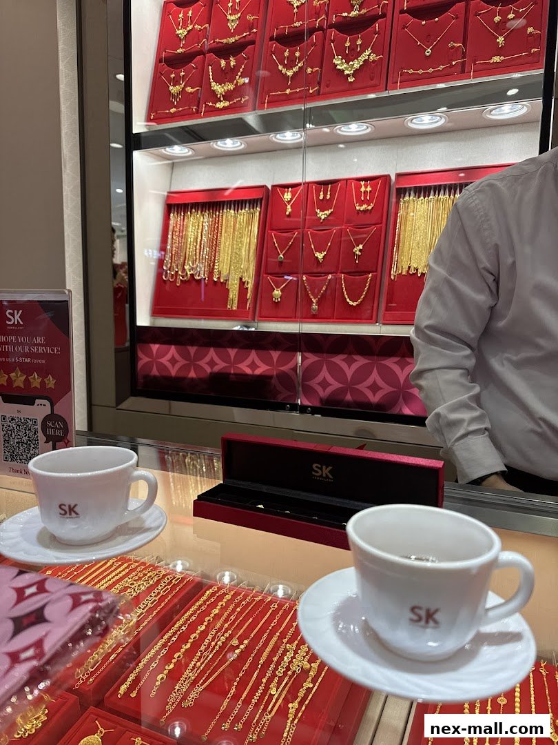 Display of gold necklaces and bracelets at SK Jewellery, with two cups and saucers on the counter.