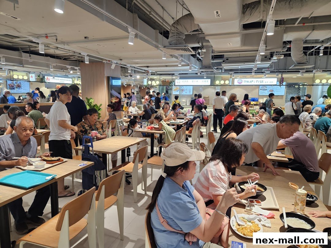 A busy food court with many people dining at tables and ordering food from various stalls.