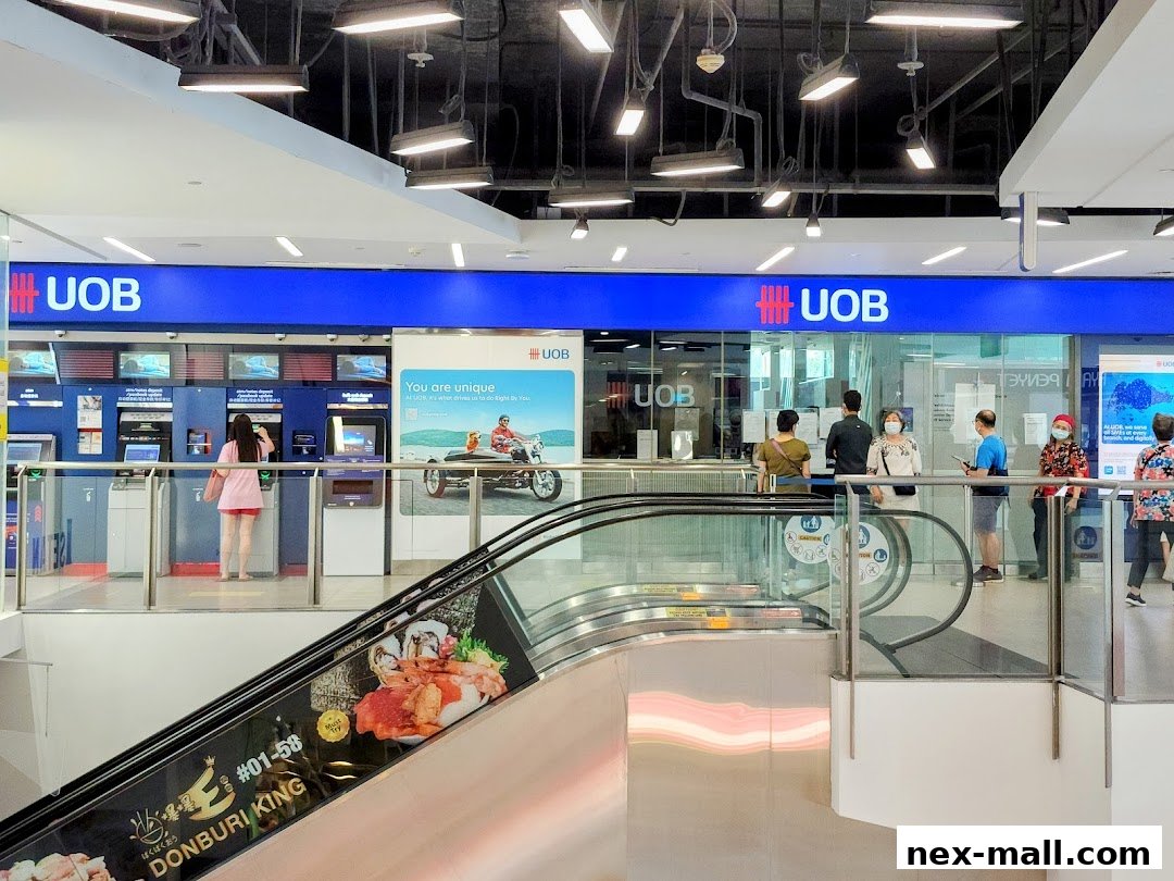 A UOB bank branch with ATMs and customers, viewed from an escalator.