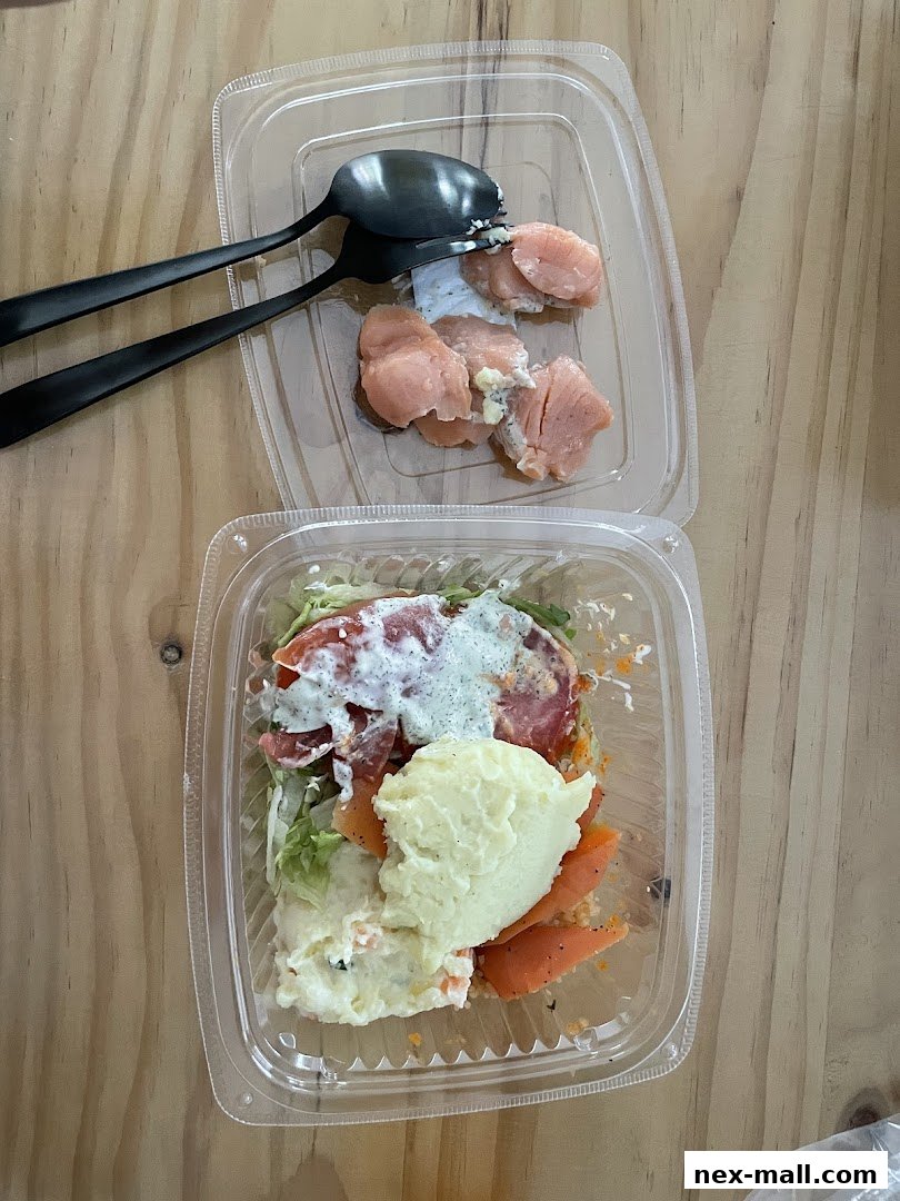 Two clear plastic containers with food, one with salmon and mashed potatoes, the other with salmon pieces.