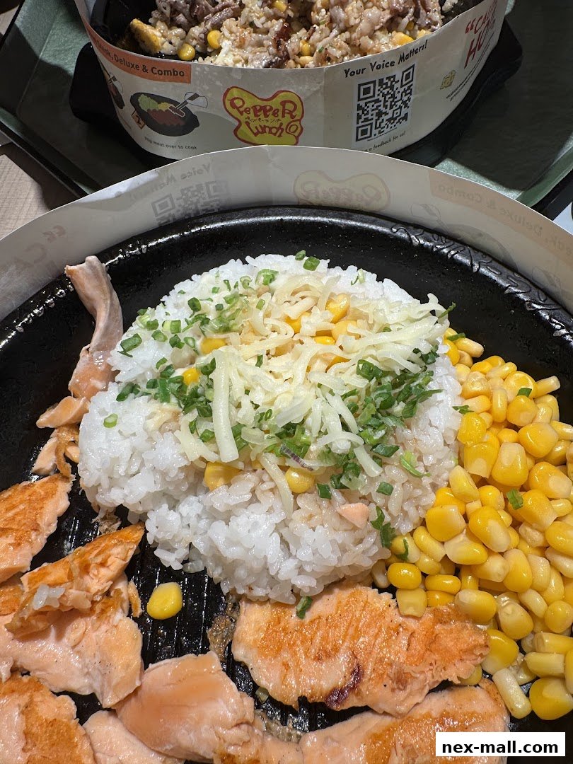A sizzling hot plate of salmon, rice, and corn, topped with cheese and chives.