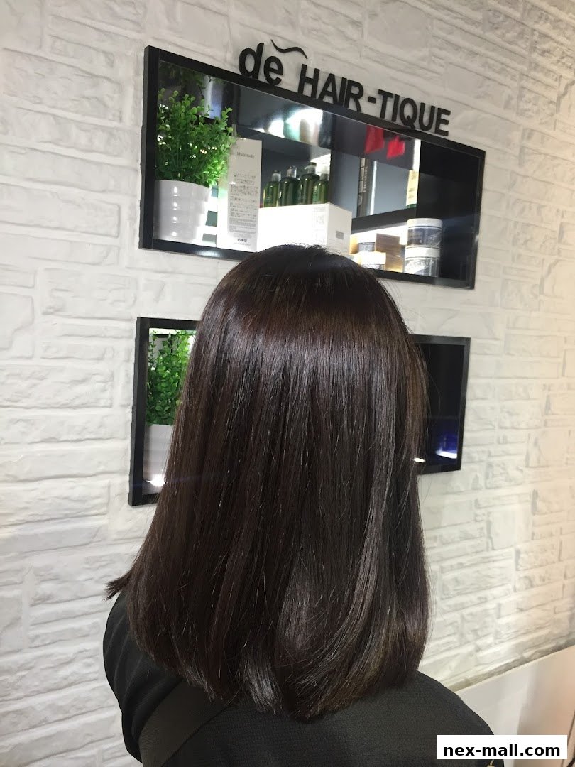 A person with freshly styled, shiny dark brown hair in a salon.