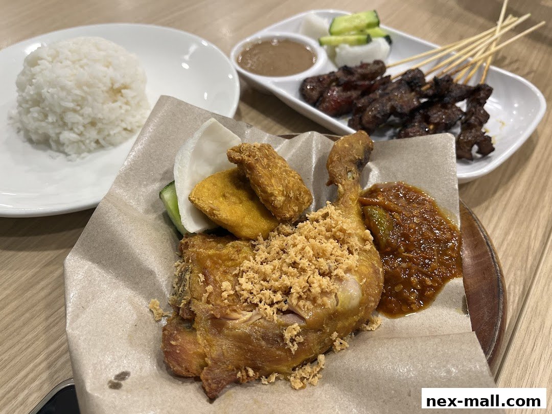 A close-up of Ayam Penyet Ria's signature fried chicken with rice and satay.