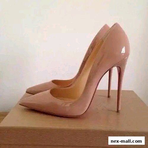 A pair of elegant, nude patent leather high-heeled shoes on a wooden surface.