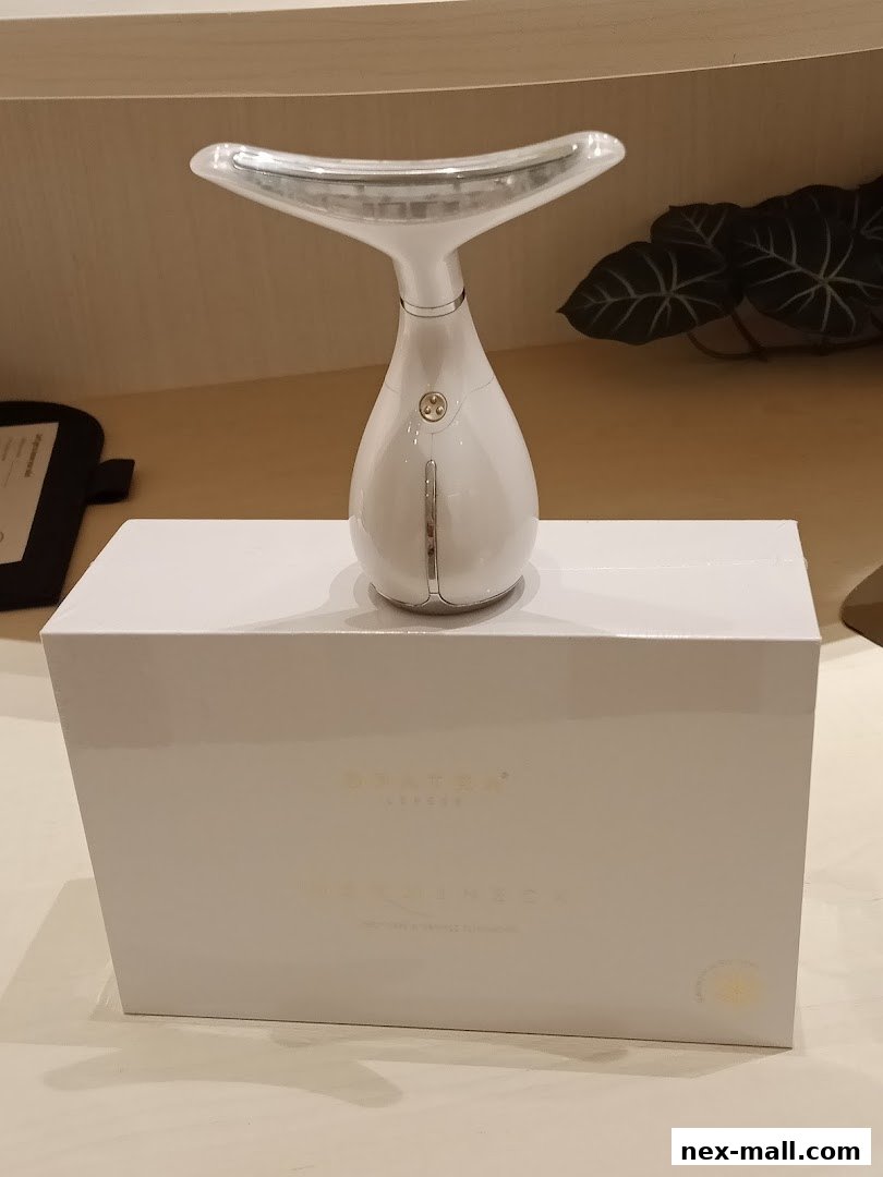 A white neck toning device is displayed on a white box, with a plant in the background.