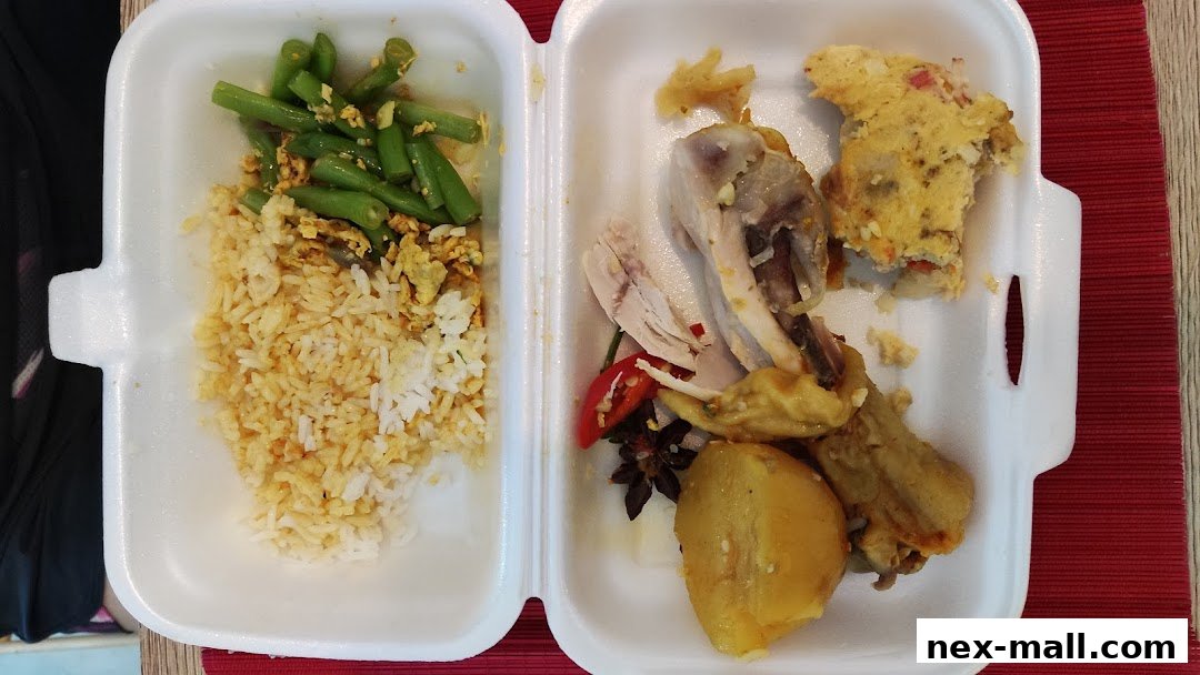A takeout container filled with rice, green beans, chicken, potatoes, and a savory omelet.