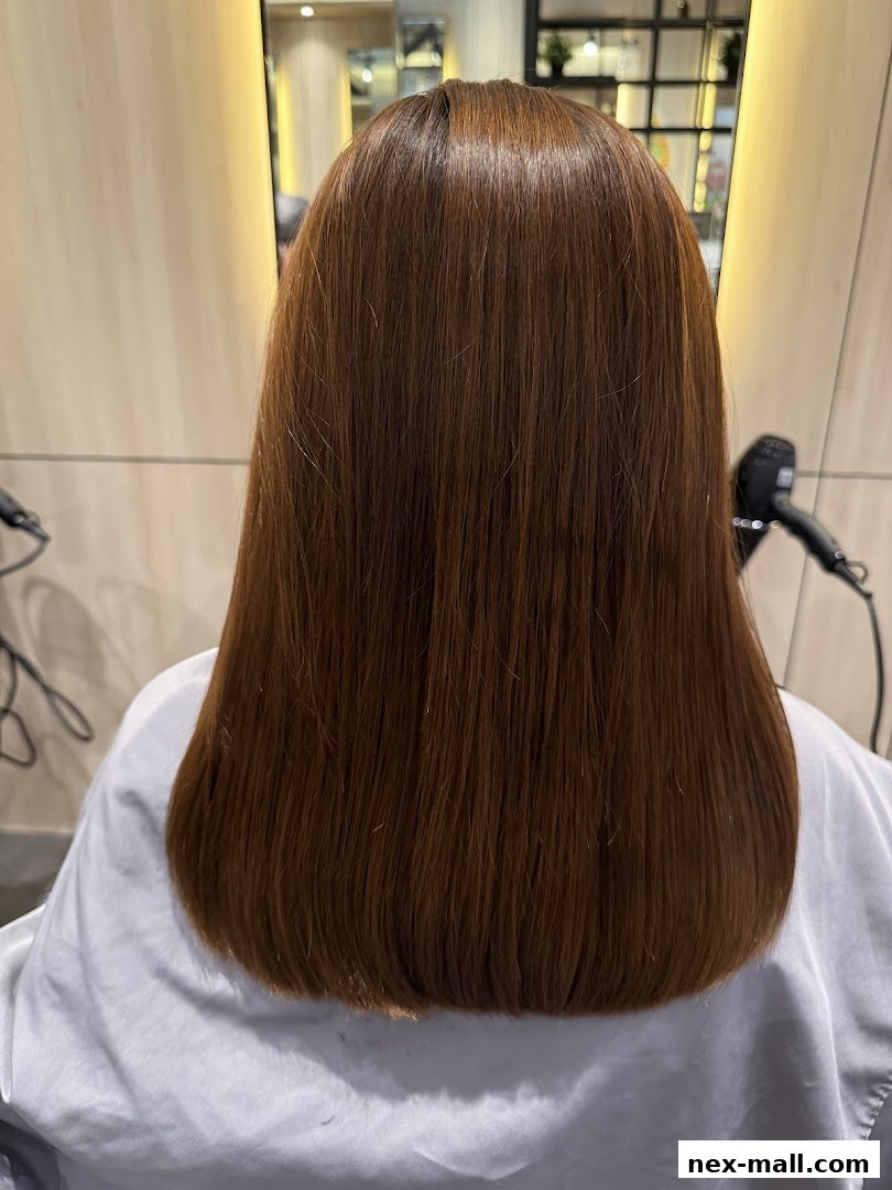 A person's back with freshly styled, long, brown hair in a salon.