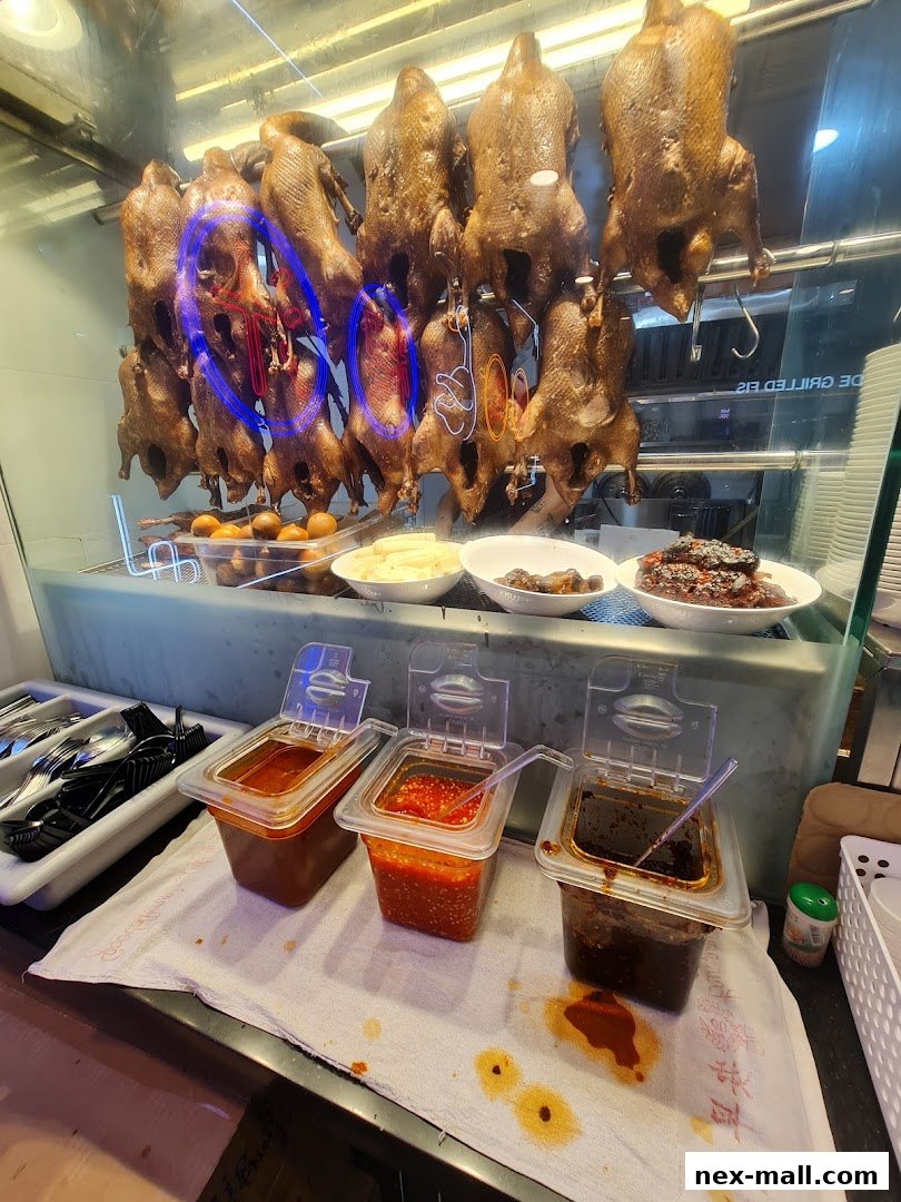 Roasted ducks hanging in a display with various dipping sauces and side dishes.