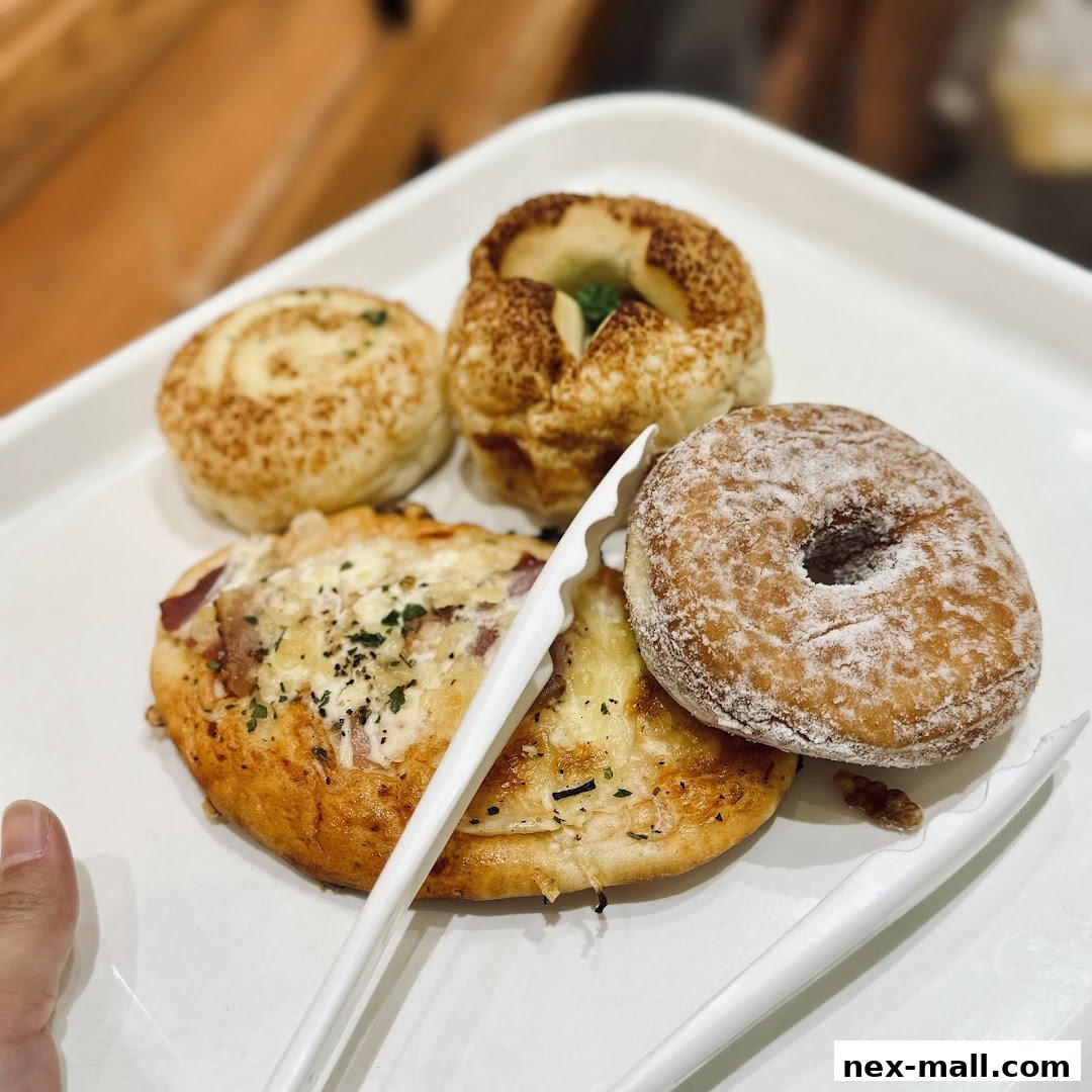A white tray holds a selection of freshly baked pastries, including a donut and savory buns.