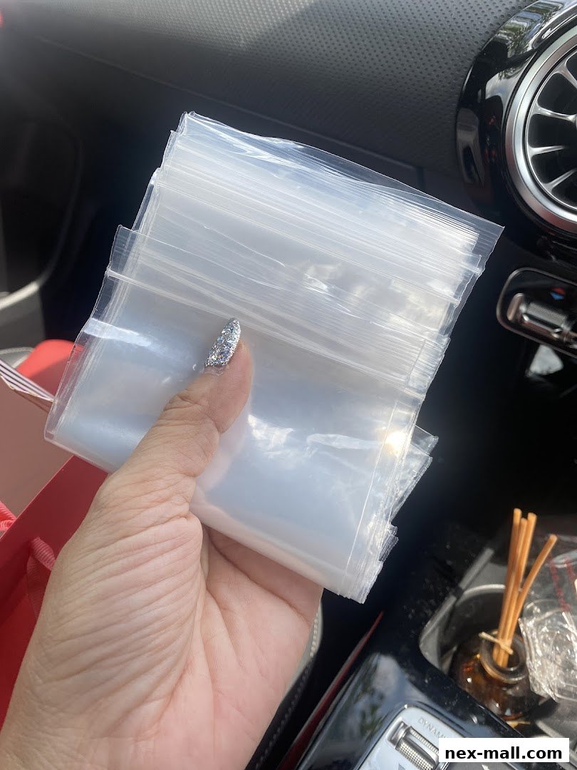A hand holds a stack of small, clear plastic bags.