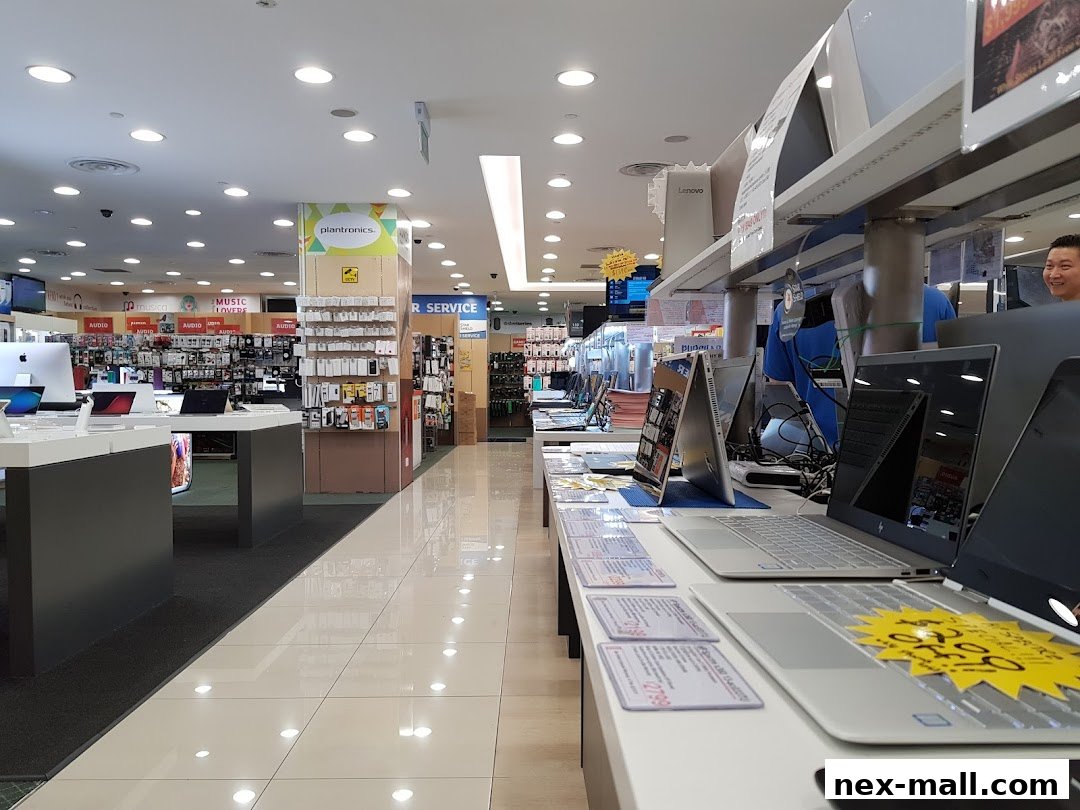 Interior view of a brightly lit electronics store showcasing laptops and accessories.