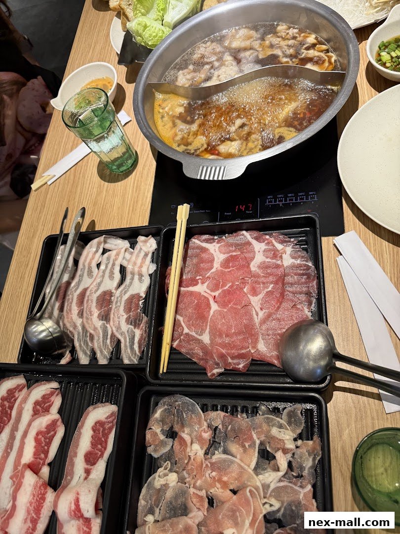 A table laden with Shabu Sai hot pot ingredients, including various meats and a bubbling broth.