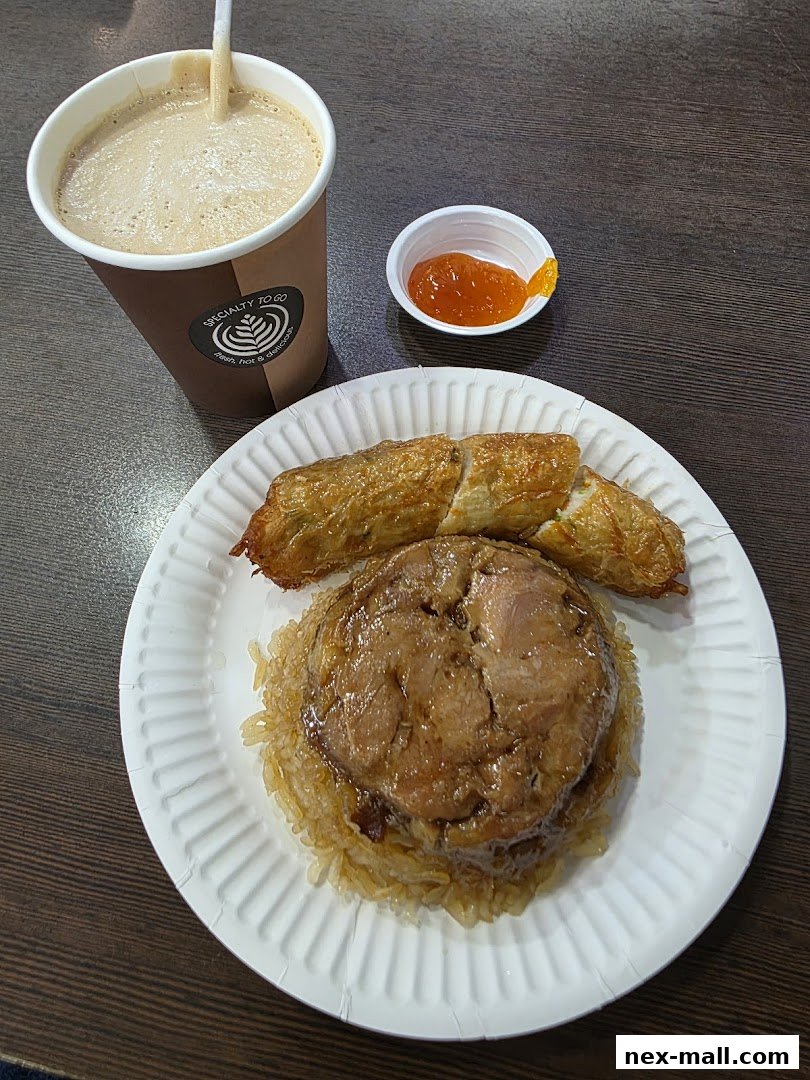 A paper plate with a serving of sticky rice topped with braised meat and two fried rolls, alongside a coffee cup.