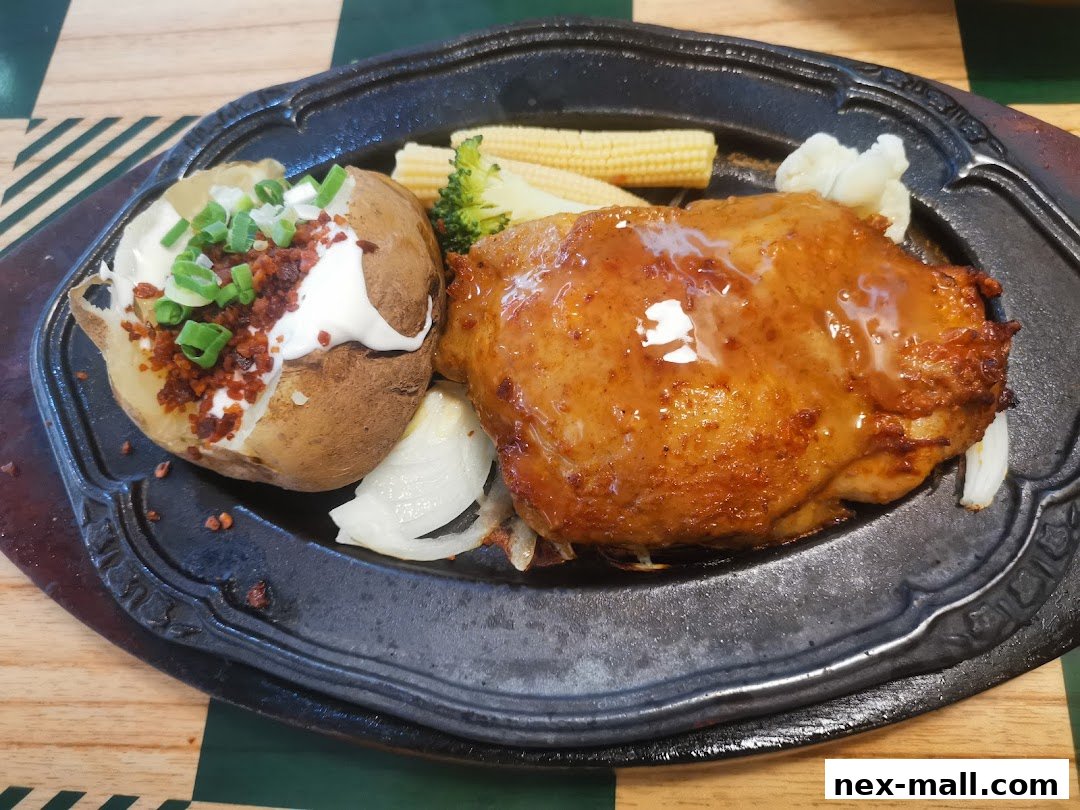 A delicious meal featuring a baked potato with toppings and a glazed chicken thigh.