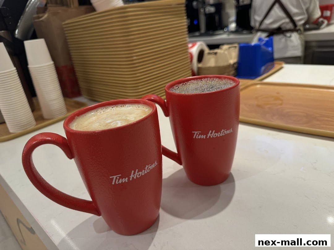 Two red Tim Hortons mugs, one with latte art and the other with black coffee.