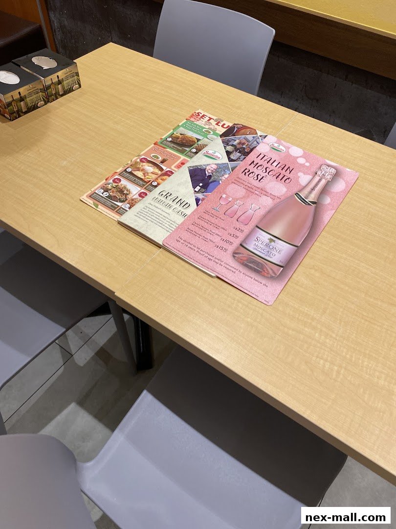 A table at Saizeriya with menus and a bottle of Italian Moscato Rose.