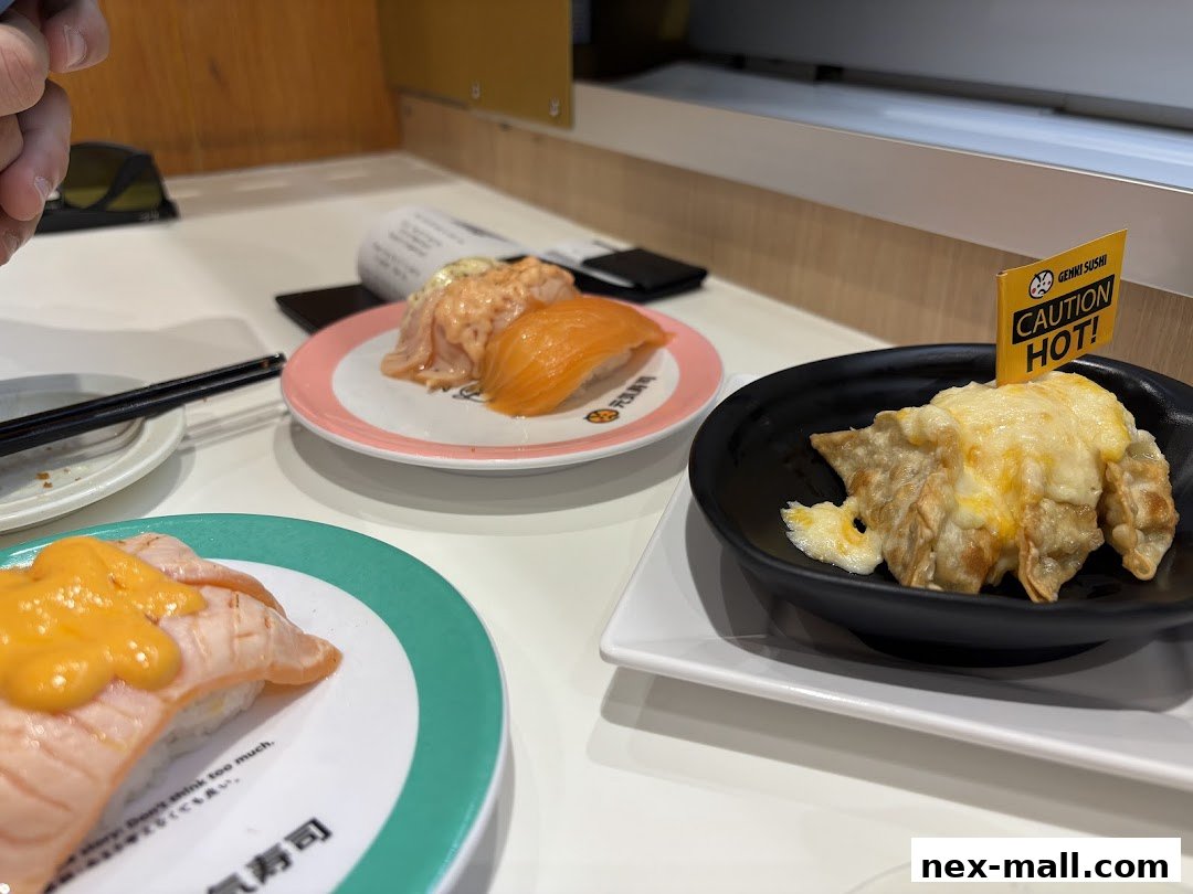 A close-up of various sushi dishes and a plate of cheesy gyoza at Genki Sushi.
