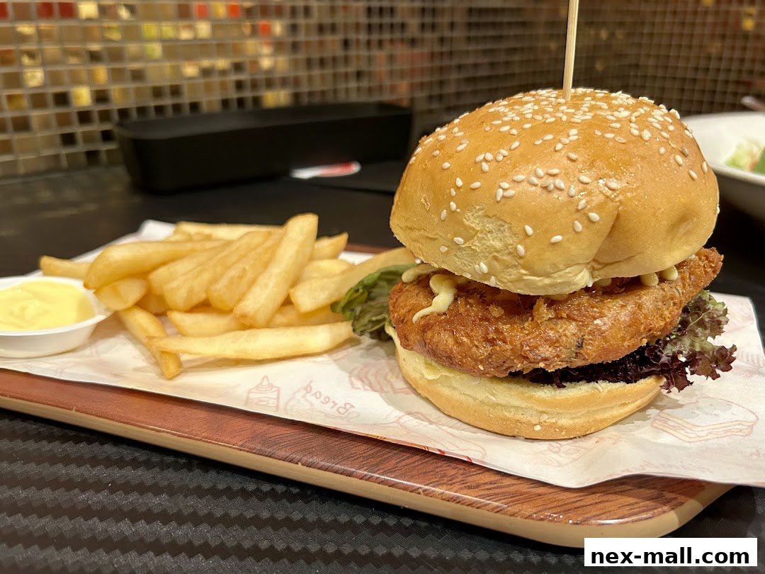 A delicious-looking burger and fries served on a wooden tray with a side of dipping sauce.