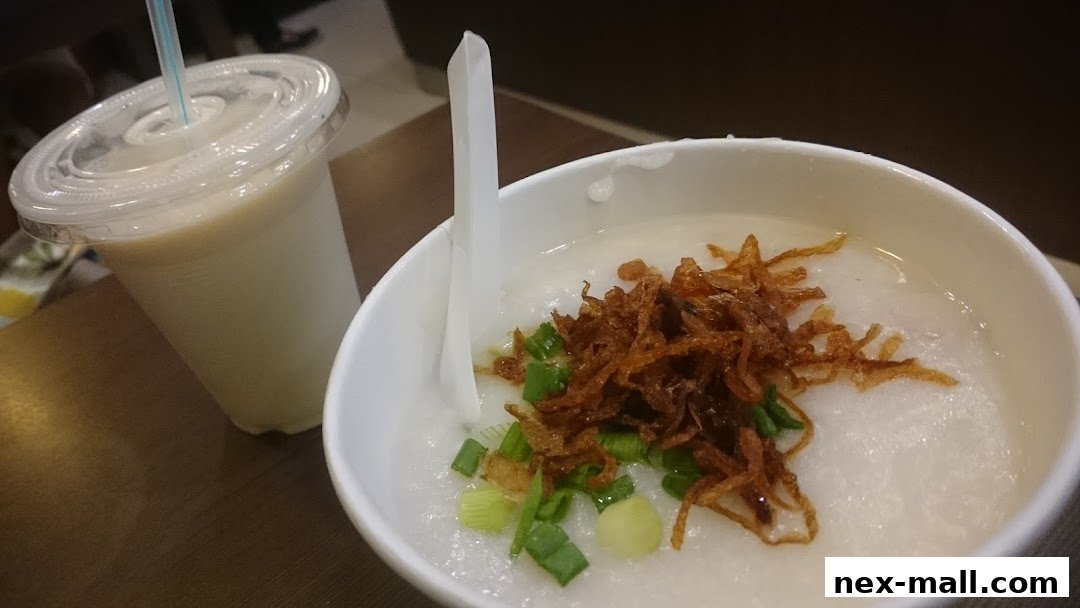 A bowl of congee topped with fried shallots and scallions, next to a drink.