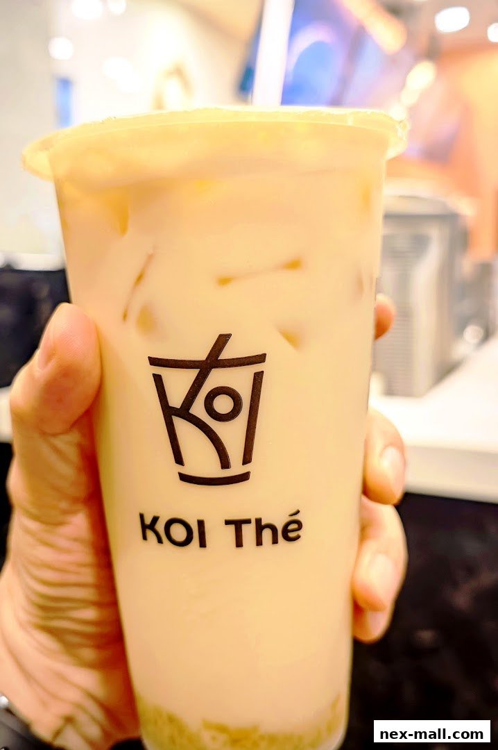 A hand holds a KOI Thé beverage with the brand logo visible on the cup.