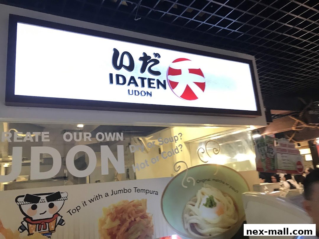 The storefront of Idaten Udon, featuring a large illuminated sign and window graphics.