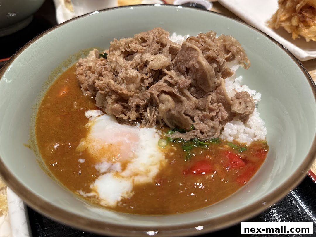 A bowl of Japanese curry rice with sliced beef and a soft-boiled egg.