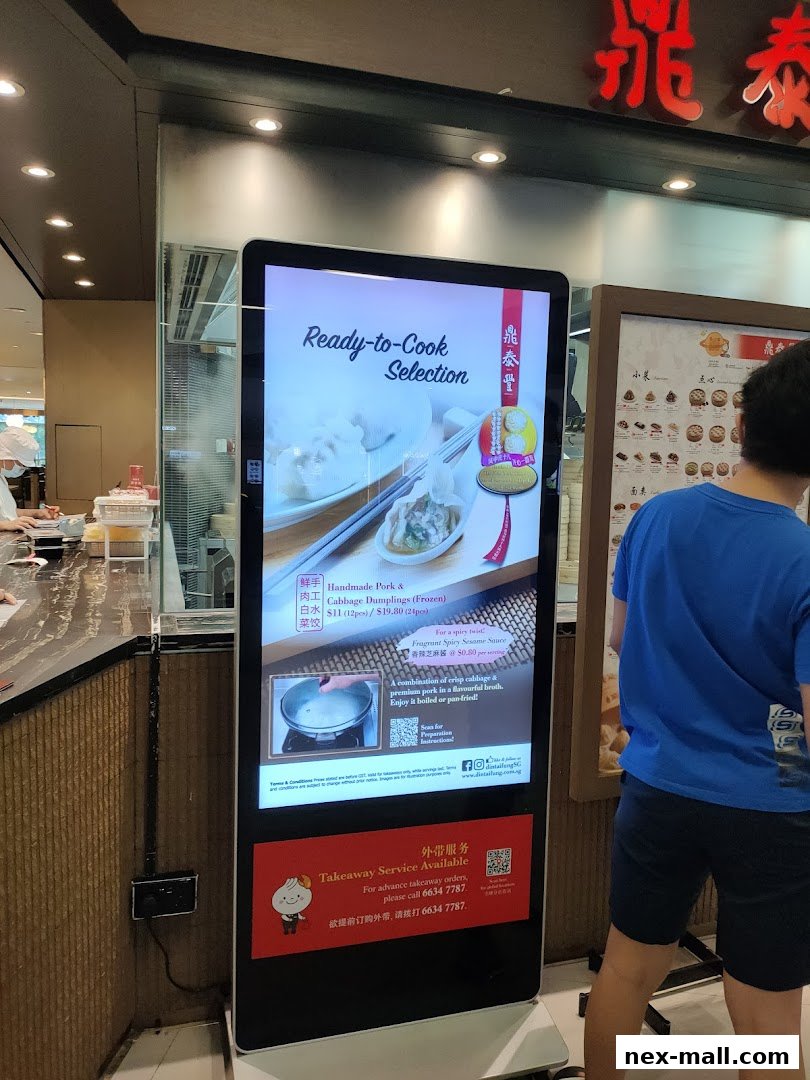 A digital display shows Din Tai Fung's ready-to-cook dumplings and takeaway service information.
