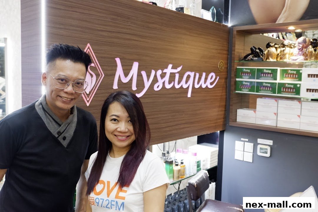 Two smiling people stand in front of the Mystique shop sign, with products displayed on shelves.