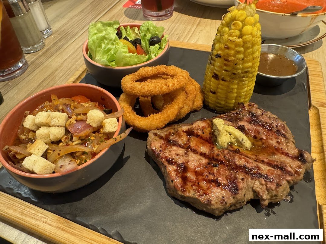 A grilled steak with corn, onion rings, salad, and a side dish.