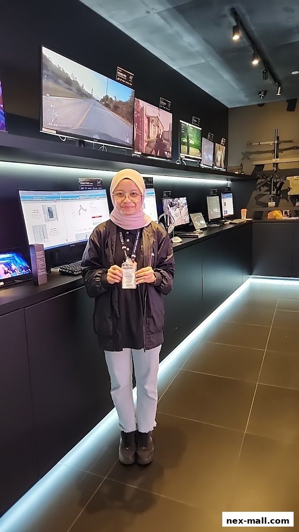 A woman stands in a modern electronics store, showcasing various displays and products.