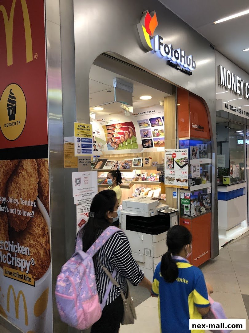 The FotoHub shop entrance with customers and a McDonald's advertisement nearby.