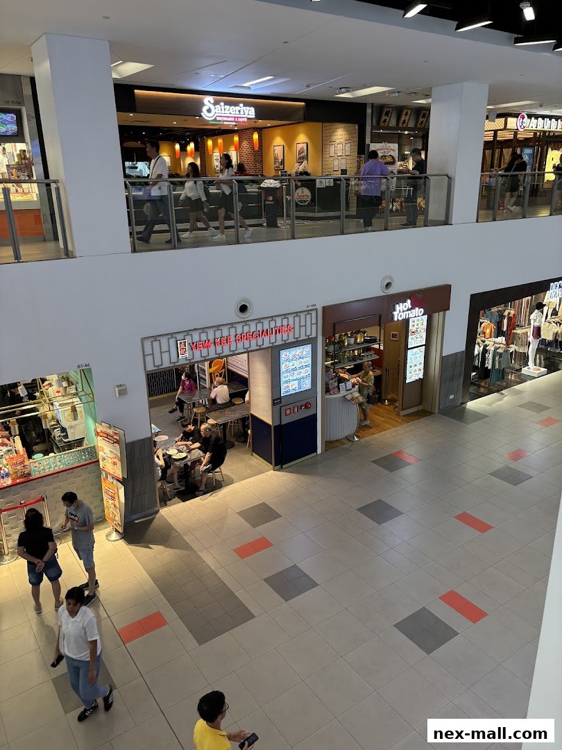 A view of a shopping mall interior showing several shops and people walking.