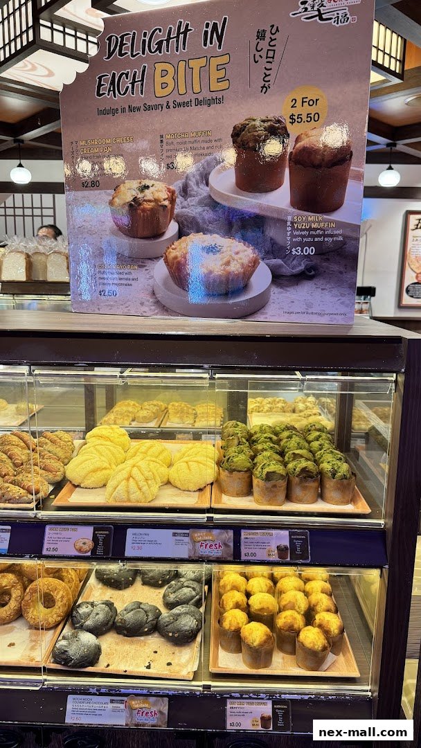 A display of various Japanese baked goods, including muffins and buns, with a promotional sign.