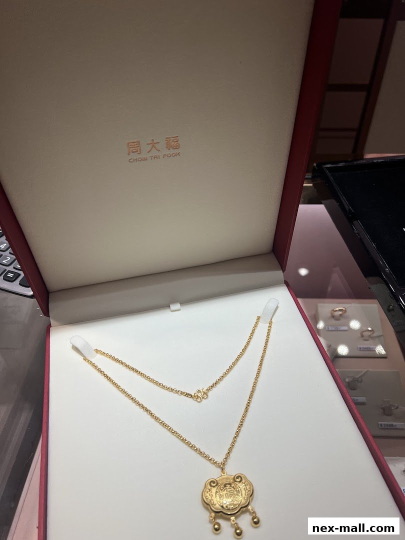A gold necklace with a traditional Chinese lock pendant displayed in a jewelry box.