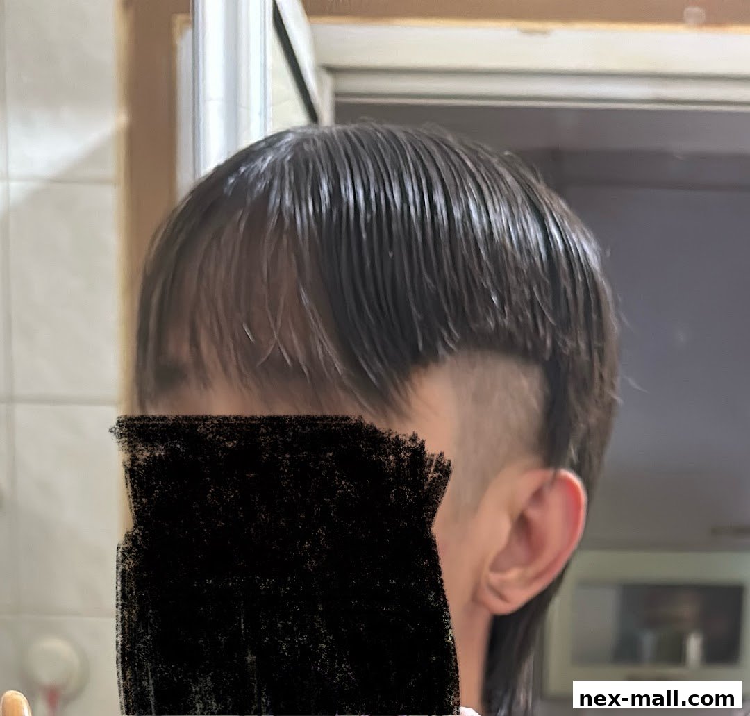 A close-up of a person's head showing a modern haircut with shaved sides and longer top.