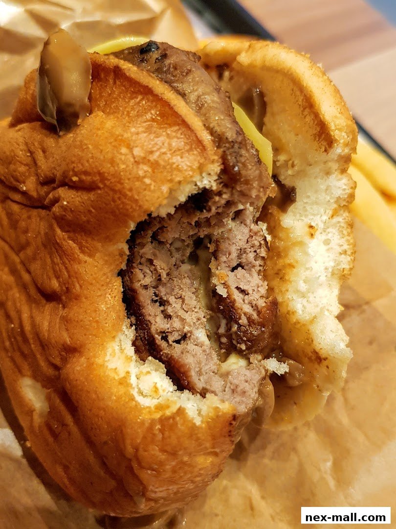 A close-up shot of a juicy, partially eaten burger with a thick patty and melted cheese.