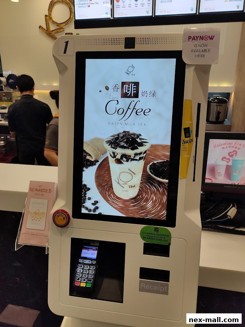A self-ordering kiosk at KOI Thé NEX displaying a coffee and milk tea beverage.
