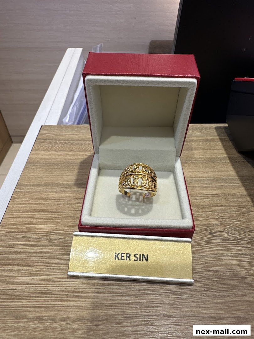 A gold ring with intricate patterns displayed in a red jewelry box.