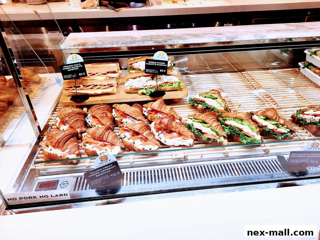 A display case filled with various sandwiches and croissants at Paris Baguette NEX.