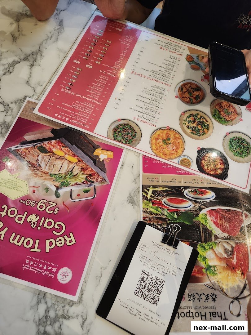 A table with menus and a receipt from Go-Ang Pratunam Chicken Rice.